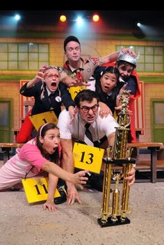 a group of people posing for a photo with a trophy in front of their faces