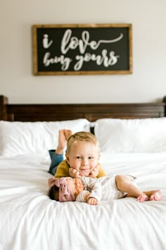 a baby laying on top of a white bed