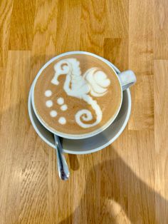 a cappuccino with white designs on it sitting on top of a wooden table