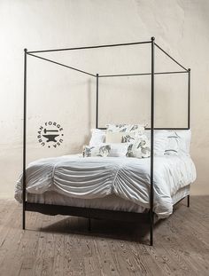 a four poster bed with white sheets and pillows