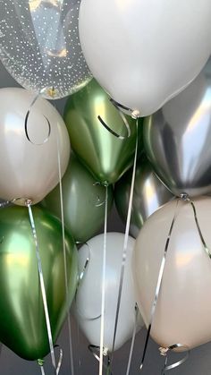 many white and green balloons are in the air