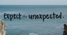 the word expect is written in black ink on a cliff overlooking the ocean