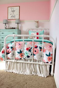 a white metal bed with pink flowers on it in a bedroom next to a dresser