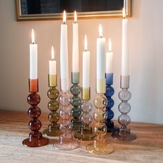 a group of candles sitting on top of a wooden table next to each other in front of a mirror