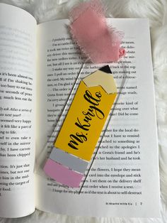 an open book with a pink and yellow lip gloss on it