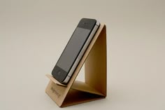 a cell phone in a wooden stand on a white surface with no one around it