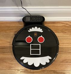 a black and white robot with red eyes sitting on the floor next to a wall