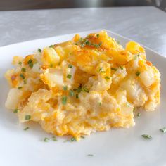 a white plate topped with an egg casserole covered in cheese and chives