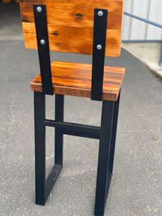 a wooden chair sitting on top of a cement floor next to a metal fence and building