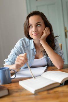 a woman sitting at a table with an open book and coffee mug in front of her