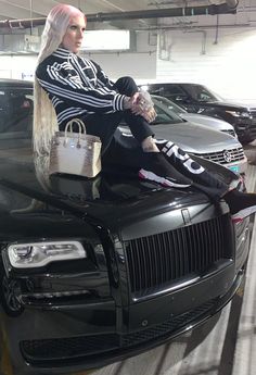 a woman sitting on the hood of a black car