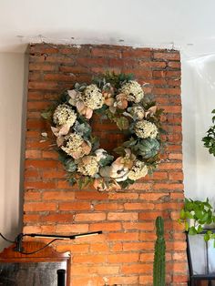 a brick wall with a wreath hanging on it's side next to a potted plant