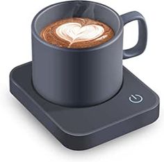 a cup of coffee sitting on top of a computer keyboard with the shape of a heart