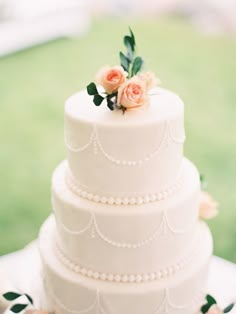 a three tiered white wedding cake with flowers on top