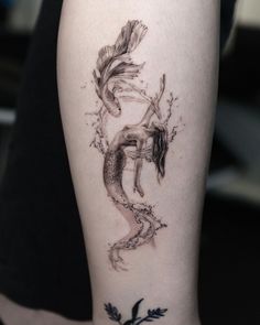 a woman's leg with a mermaid tattoo on it