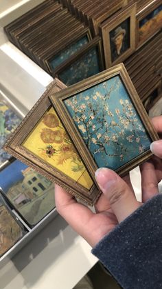 a person holding three paintings in their hands