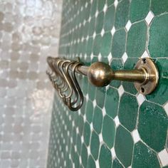 a green and white tiled wall with brass handles