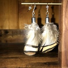 pair of white and black zebra print slippers dangling from hooks on wooden surface with wood background