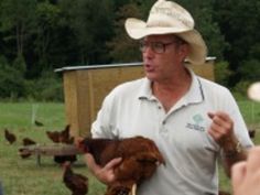 a man wearing a cowboy hat holding a chicken