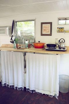 the kitchen counter is covered with white curtains