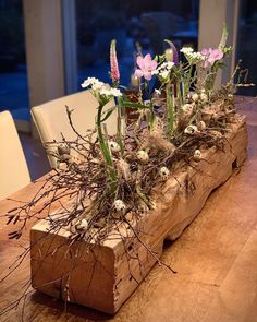 a wooden table topped with flowers and branches