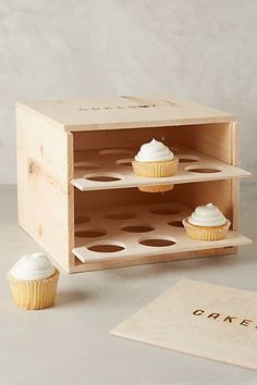 two cupcakes sitting on top of a wooden box next to a sign that says cake