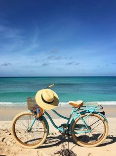 a blue bicycle with a hat on the beach