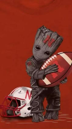 a baby groote holding a football and helmet on top of a red background