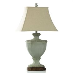 a lamp that is sitting on top of a white table with a beige shade over it