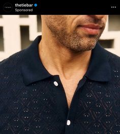 a close up of a person wearing a black shirt with white dots on the collar