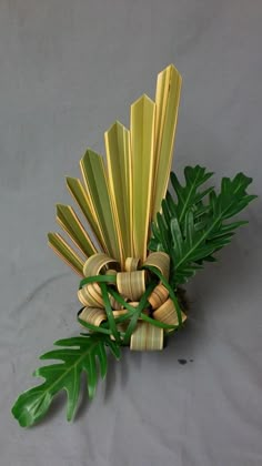 an arrangement of bamboo sticks and leaves on a gray surface with a white cloth behind it