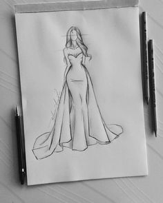 a drawing of a woman in a long dress on a piece of paper next to some pens