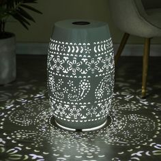 a white vase sitting on top of a table next to a chair and potted plant