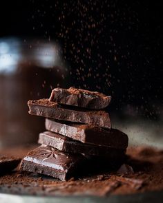 there are chocolate pieces stacked on top of each other and sprinkled with cocoa powder