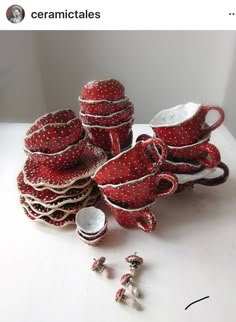 a pile of red and white dishes sitting on top of a table