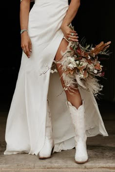 a woman in white boots and dress with flowers on her leg, holding a bouquet