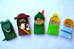 five felt dolls are lined up on a white surface