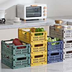 four crates filled with fruits and vegetables sitting on a kitchen counter next to a microwave