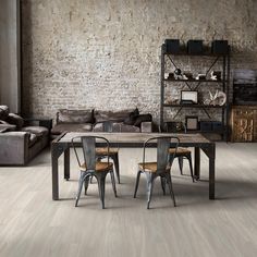 a living room filled with furniture and a wooden table in front of a brick wall