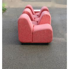 a pink couch sitting on top of a cement floor next to a parking lot with no one in it