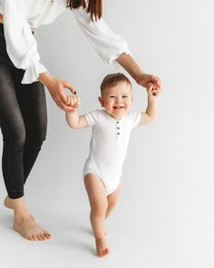 a woman holding the hand of a baby