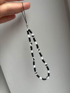 a hand holding a black and white beaded necklace on a string that is attached to a wall