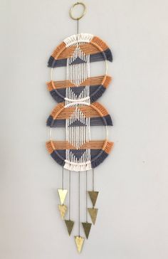 a wall hanging made out of woven and wooden pieces with metal triangles on the sides