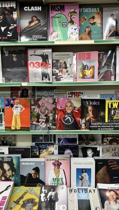 a book shelf filled with lots of books on top of each other and magazines in front of them