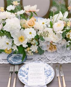 the table is set with flowers and place settings for an elegant wedding reception in blue and white