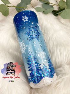 a blue and white tumble with snowflakes on it sitting next to some green leaves