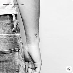 two people holding hands with tattoos on them