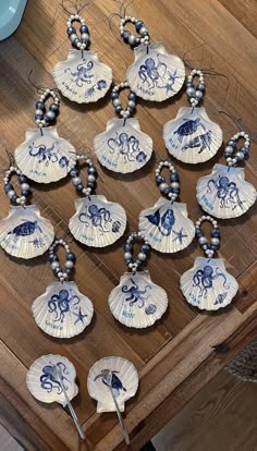 twelve blue and white seashells are arranged on a table with beaded necklaces