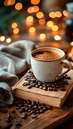 a cup of coffee sitting on top of a wooden table next to some coffee beans