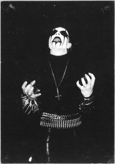 a black and white photo of a man with his hands in the air, wearing an evil mask